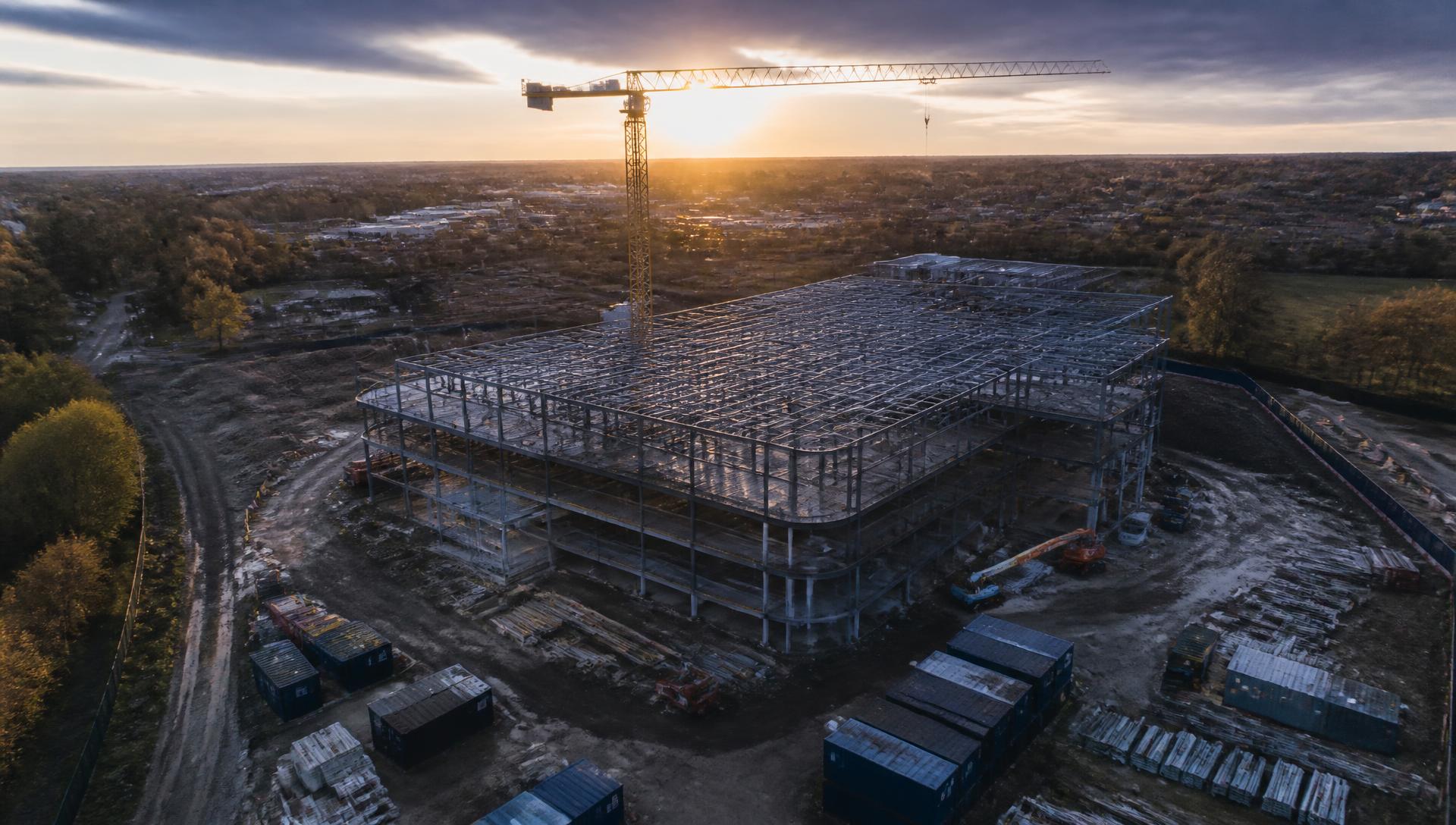 Aerial view of a construction site with a tower crane and steel frame structure